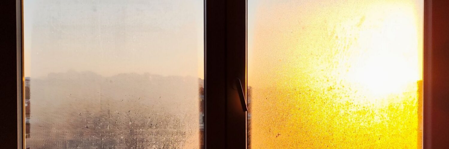 Two small frosted window panes with an orange sunrise glowing through one