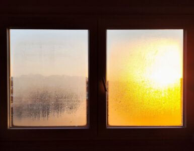 Two small frosted window panes with an orange sunrise glowing through one