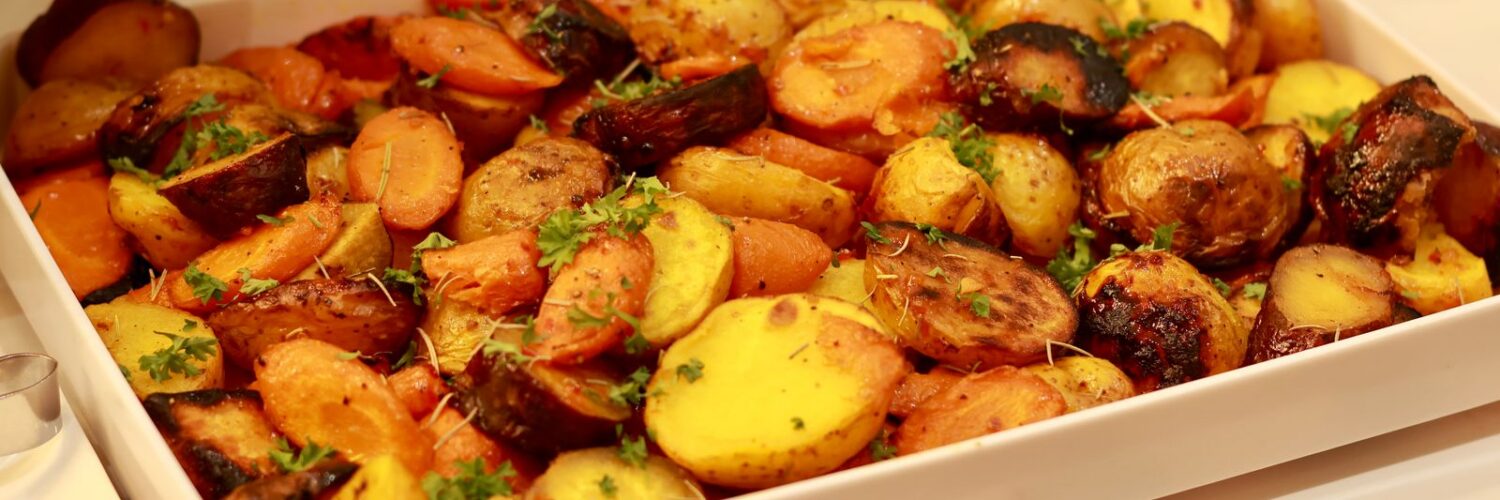 Roasted potatoes and carrots with herbs in a white serving dish