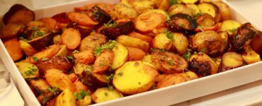 Roasted potatoes and carrots with herbs in a white serving dish