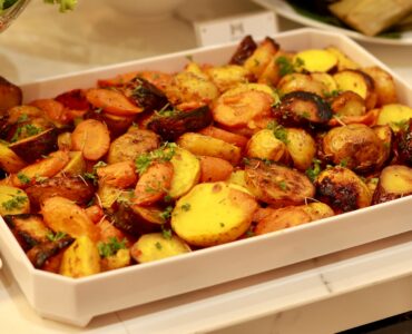 Roasted potatoes and carrots with herbs in a white serving dish