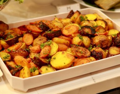Roasted potatoes and carrots with herbs in a white serving dish
