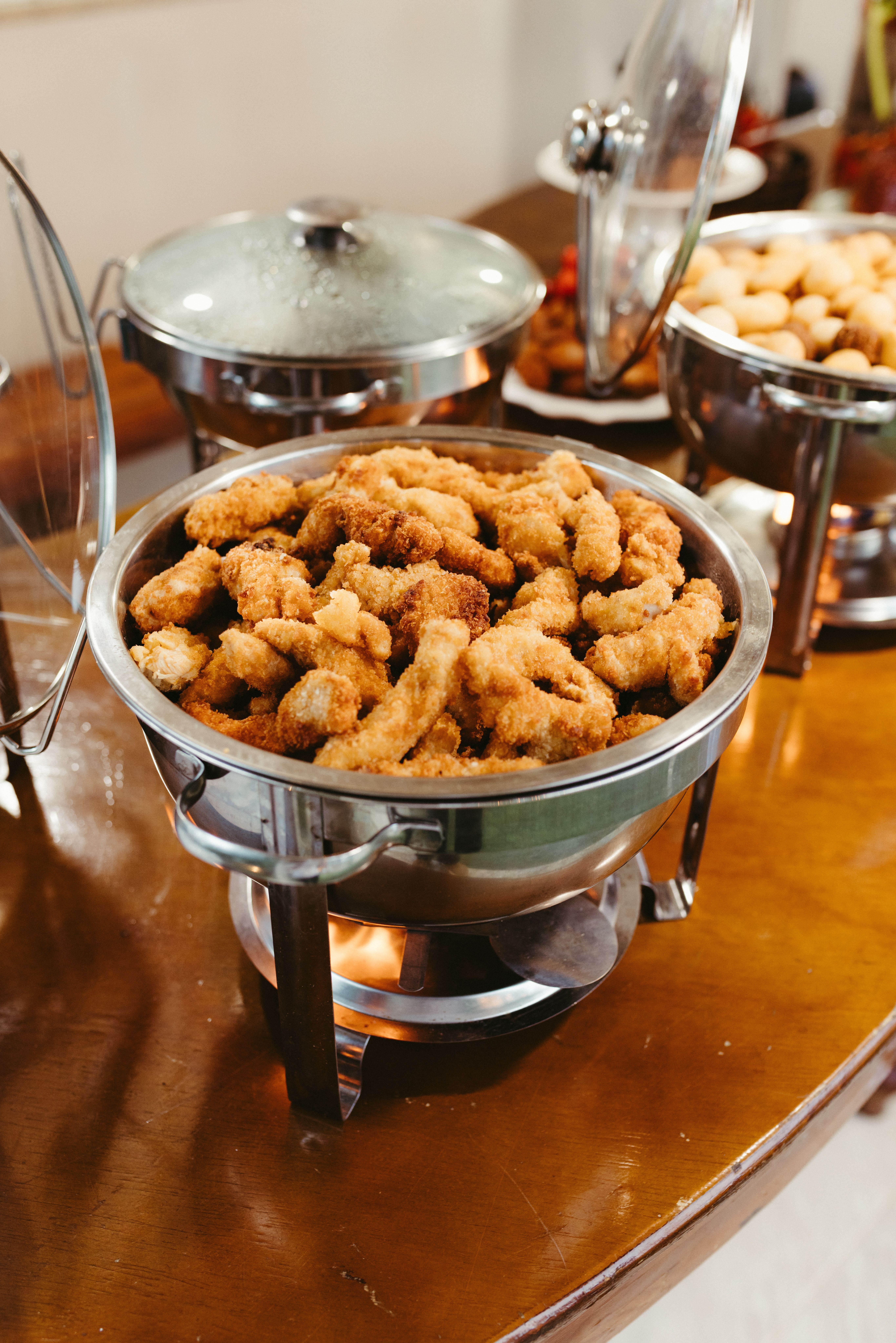 Fried food kept hot in a metal chafing dish on a buffet line