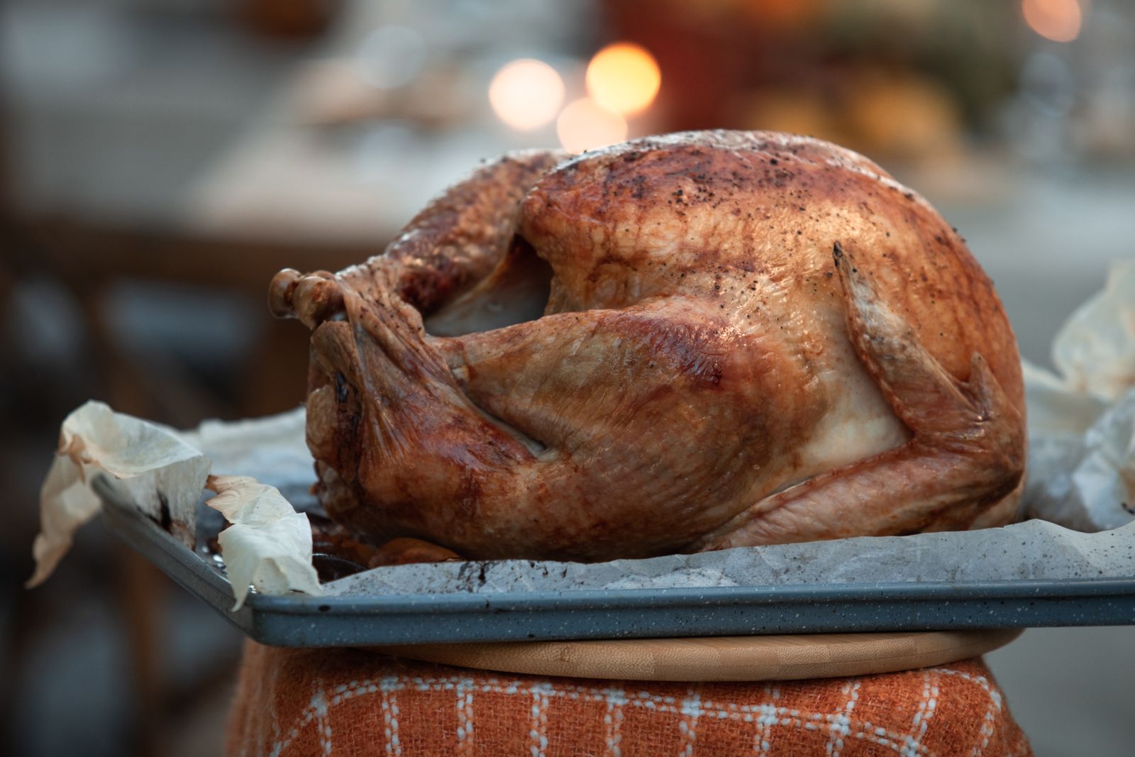 A whole roasted turkey with browned skin resting on a blue baking tray lined with parchment paper