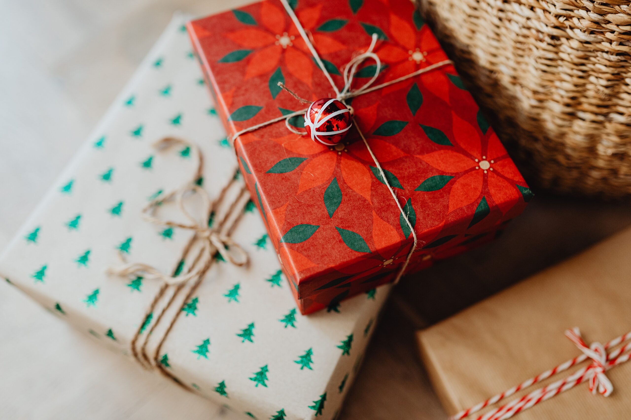 Gift boxes in red poinsettia paper and green tree-pattern paper, tied with twine