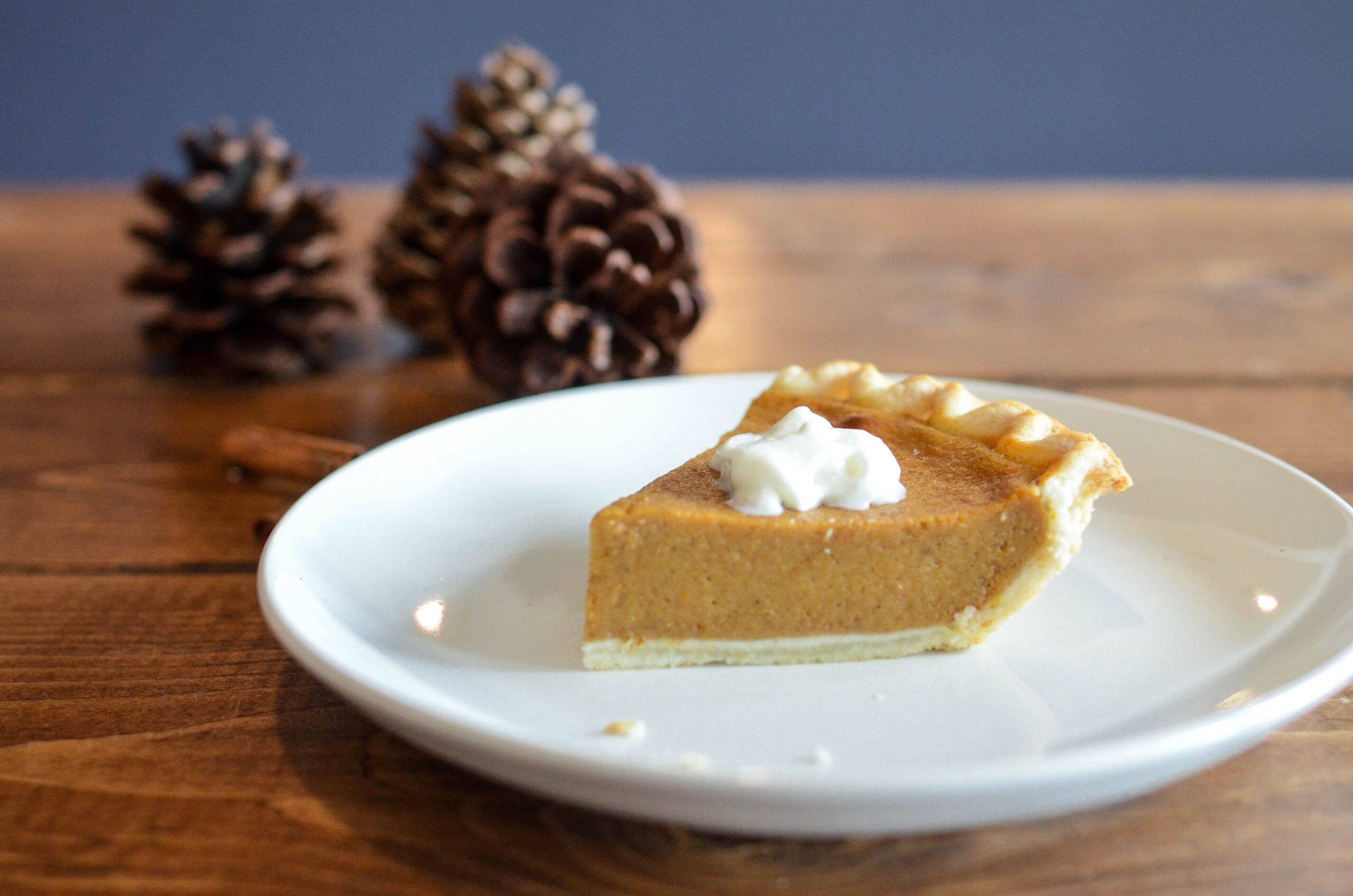 A slice of pumpkin pie with whipped cream on a white plate