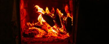 Logs burning behind the open door of a wood stove