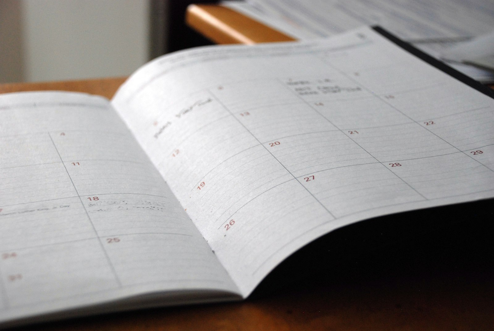 An open monthly planner lying on a wooden desk