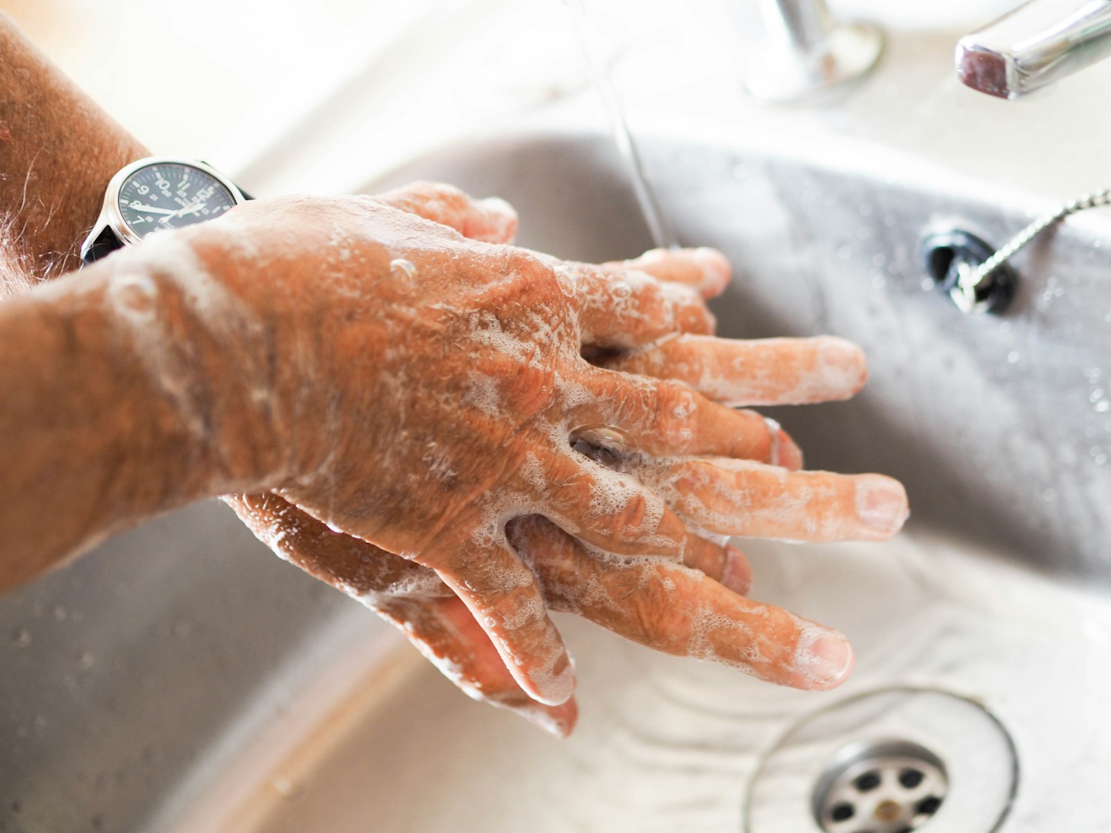 Hands being washed under running water at a sink