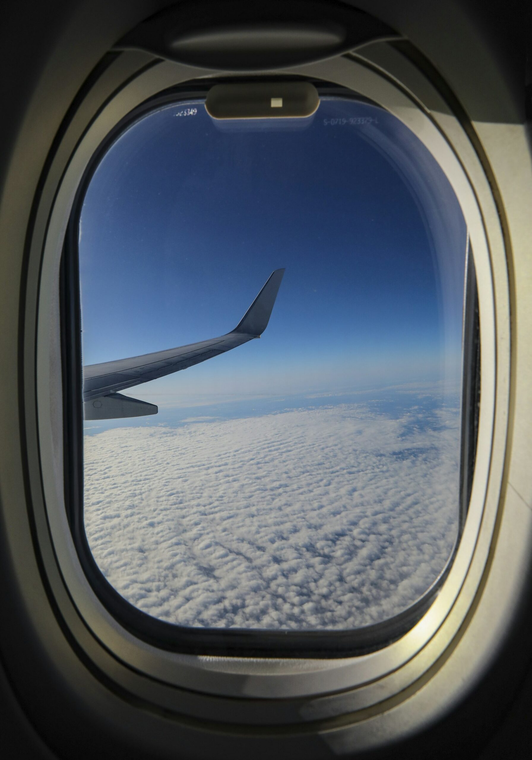 A wing tip and a layer of clouds seen through an airplane window