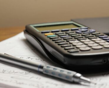 A calculator and a pen resting on a sheet of paper