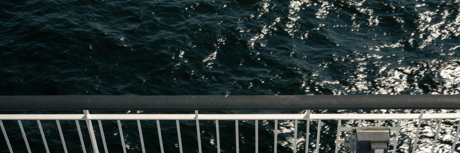 A ship's rail overlooking dark, sparkling ocean water