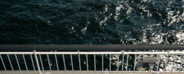 A ship's rail overlooking dark, sparkling ocean water
