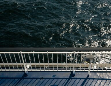 A ship's rail overlooking dark, sparkling ocean water