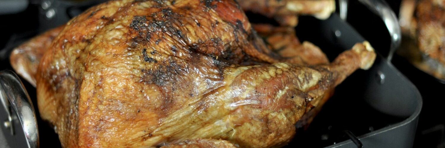 A golden-brown roasted turkey in a roasting pan
