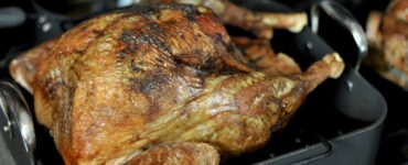 A golden-brown roasted turkey in a roasting pan