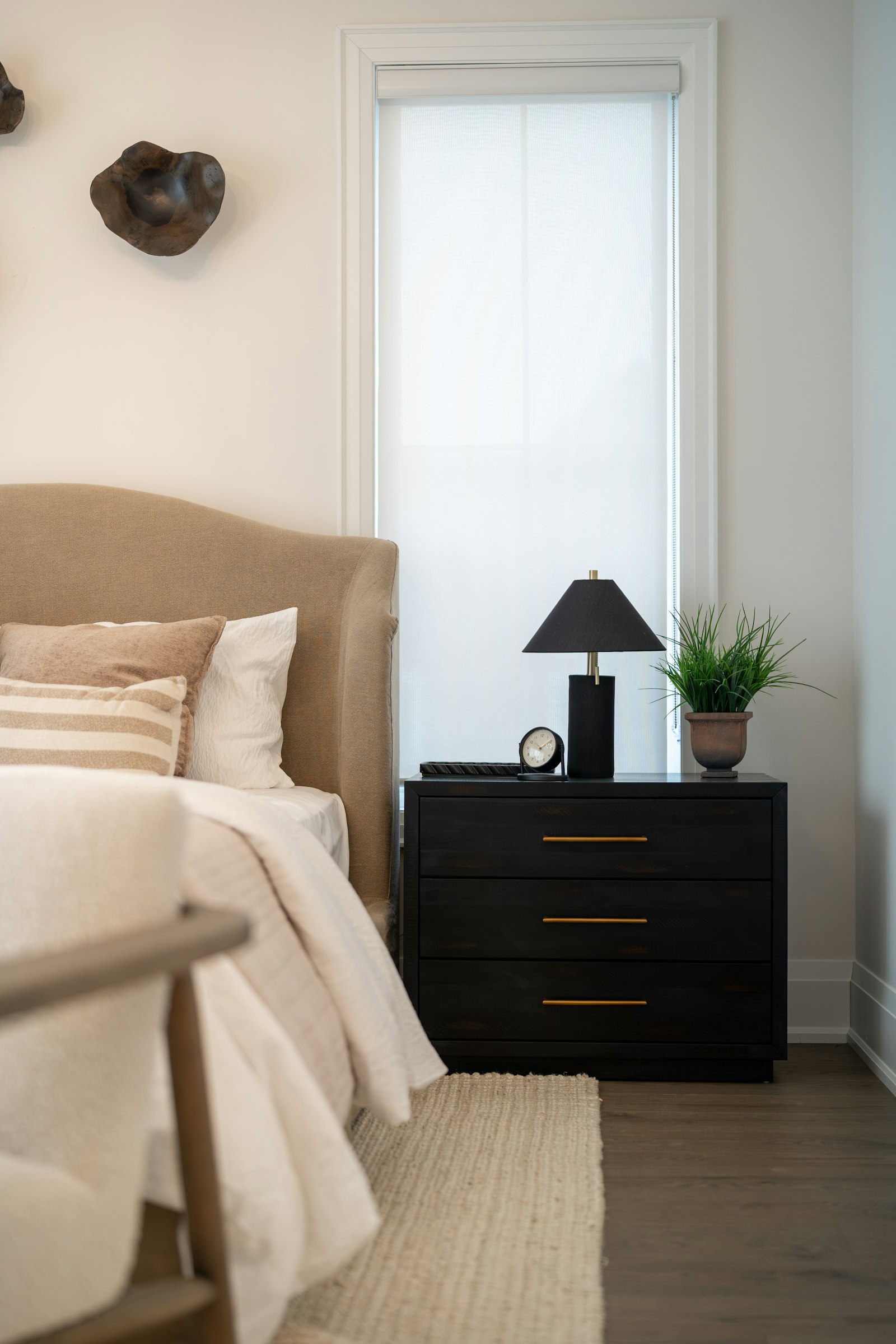 A modern bedroom with a black nightstand and a lamp beside the bed