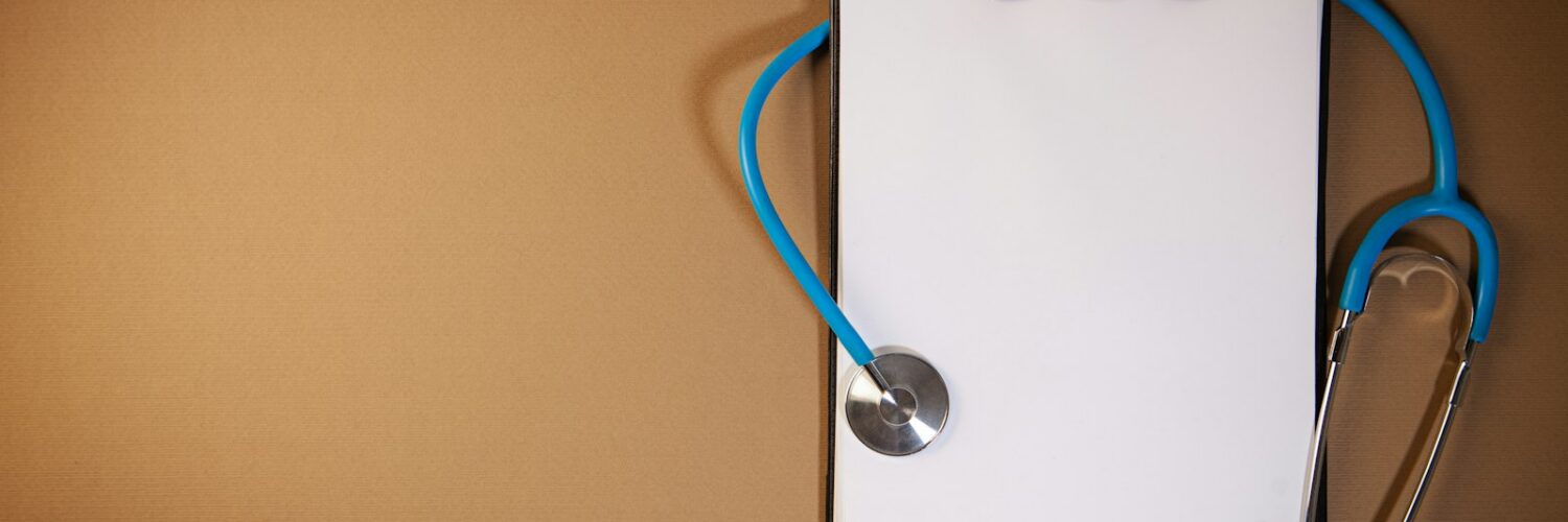 A clipboard with a stethoscope laid on top against a brown background